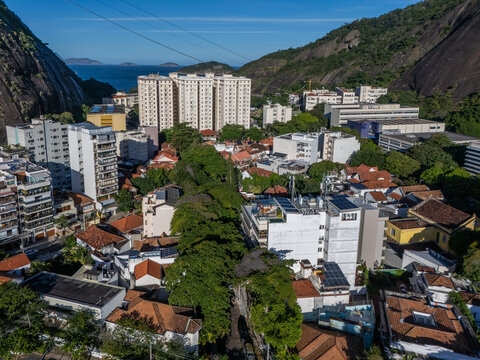 Aerial view of Urca neighborhood with dense residential housing, red-tiled rooftops, and high-rise buildings nestled between granite mountains in Rio de Janeiro, Rio de Janeiro, Brazil.