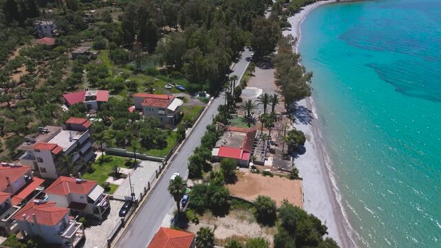 Aerial Drone View Following Motorcyclist on Scenic Coastal Road Along Turquoise Sea in Peloponnese, Greece