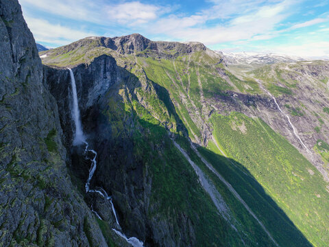 Aerial view of the Mardalsfossen waterfall cascading down a steep rocky cliff face surrounded by lush green mountains and rugged terrain in Molde, More og Romsdal, Norway.