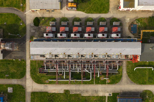 Aerial view of an industrial facility featuring a long rectangular building with complex piping systems and surrounding green grounds in Hrusky, South Moravian Region, Czechia.