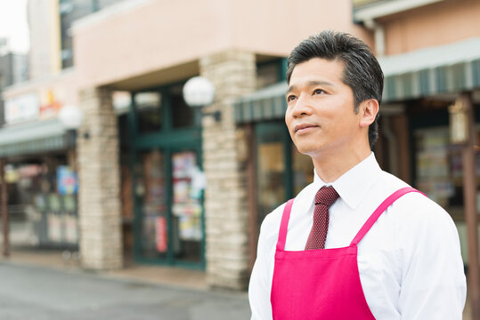 スーパーマーケットの入口で出迎える40代男性店員
