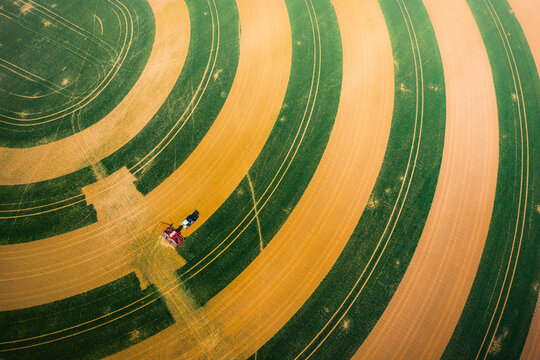 Aerial view of a combine harvester working in a field with distinct circular crop patterns in Chvalkovice, Hradec Kralove Region, Czechia.