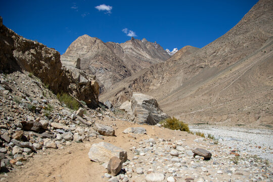 View of the rugged rocky terrain and mountain slopes near K2 Base Camp under a clear blue sky in Ghakhar, Gilgit, Pakistan.