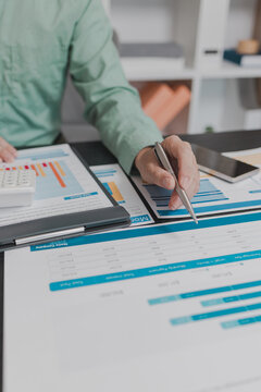 Business professional reviewing financial statements, analyzing performance reports and comparing budget data across multiple documents and devices to support informed business decisions.