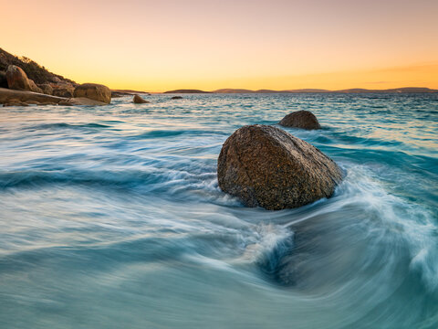 View of Frenchman Bay featuring large granite boulders in the turquoise ocean with smooth wave motion at sunset in Frenchman Bay, Western Australia, Australia.