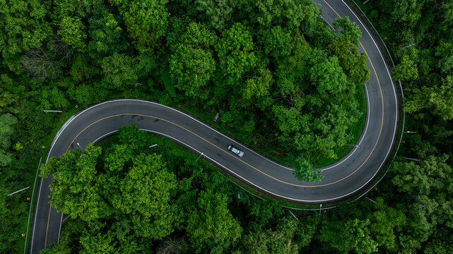 Aerial view mountain curve road in green forest, Mountain forest road surrounds natural forest, Winding road through lush green forest road tree.