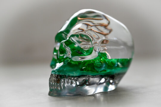 Orgone generator skull with green quartz crystal on white marble, mystical spiritual concept