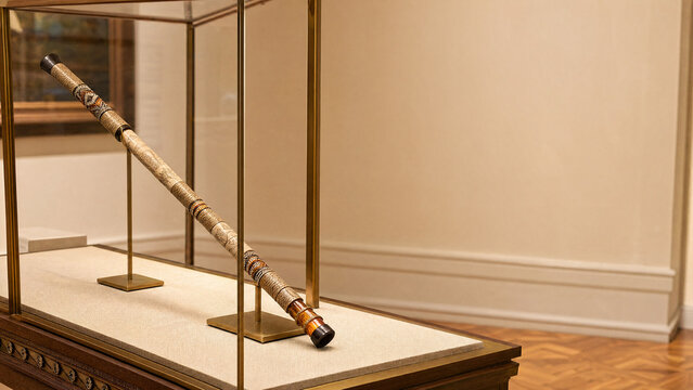 An ornate ceremonial blowpipe displayed in a museum case.