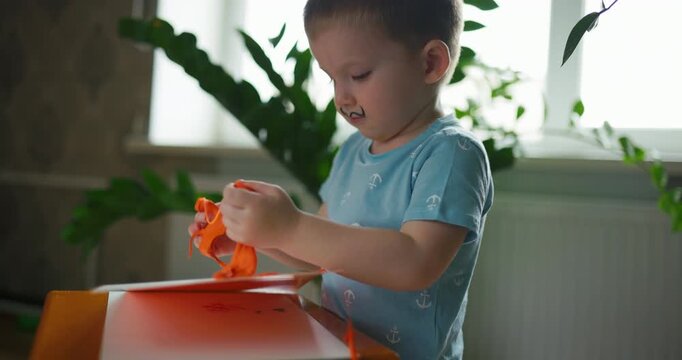 Slow motion of a cute playful child making shapes from orange play dough
