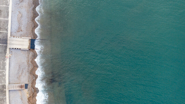 Aerial view of the turquoise sea and pebble beach at Freshwater Bay with waves crashing on the shore Freshwater, Isle of Wight, United Kingdom.