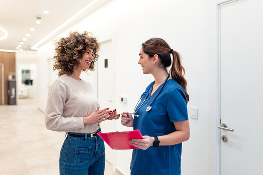 Friendly doctor talking with a patient during a consultation in a bright hospital hallway. Healthcare, medicine, doctor-patient relationship, professional advice, health, wellness, and care concept.