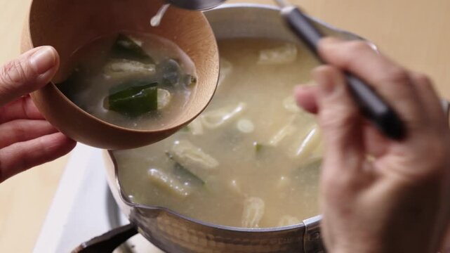 Serving freshly made miso soup with wakame and tofu into a bowl