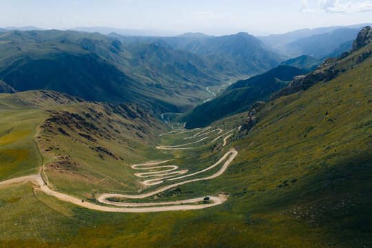 Aerial view of the winding switchback turns of the 33 Parrots Pass through the lush green mountains and deep valley of Jety - Oguz, Issyk-Kul Region, Kyrgyzstan.