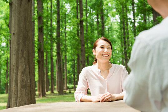 森のテーブルでくつろぐ40代夫婦