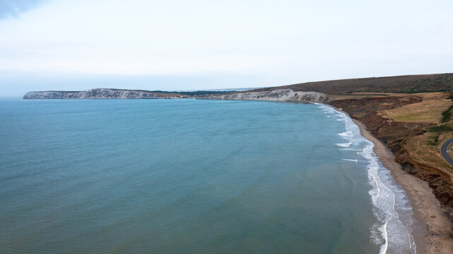 Aerial view of the white cliffs and sandy beach at Compton Bay with gentle waves washing ashore Newport, Isle of Wight, United Kingdom.
