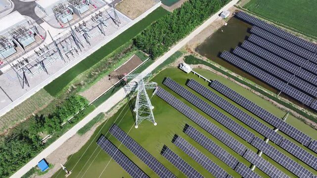 Aerial view of photovoltaic power station with transmission towers coexisting alongside farmland