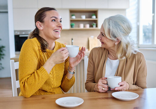 Portrait of mother and daughter  having fun, chating drinking coffee, sitting and hugging  at home, family life, parenting, love and bonding concepts