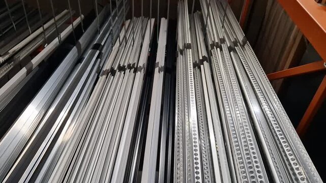 Various types of aluminum profiles (angular, T-shaped) on the shelf of a building materials store. Aluminum profiles on a rack in a building hypermarket. A wide range of fittings for repair