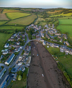 Aerial view of Frogmore Creek with tidal mudflats surrounded by residential houses and rolling green fields in Kingsbridge, South Devon, United Kingdom.
