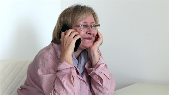 Happy senior woman smiling during a phone call at home. Mature woman using smartphone for communication, family connection or online service.