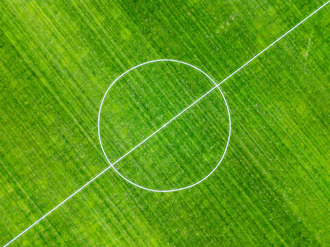 Aerial view of the center circle and halfway line on a vibrant green football field in Poland.