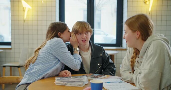 Teenagers sharing secret during study group discussion