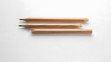 Obraz premium Three simple wooden pencils arranged in a row on a clean white background
