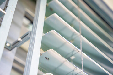 Naklejka premium Close up of aluminum window blinds with tilt mechanism and slats. Sunlight regulation and privacy protection concept for modern buildings