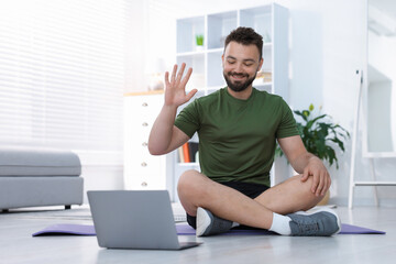 Fototapeta premium Online fitness trainer. Man watching tutorial on laptop at home