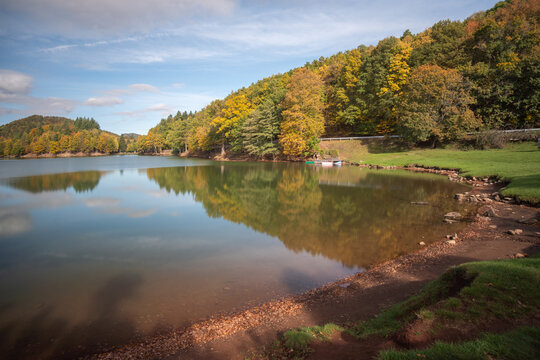 View of Pocuvadlo Lake surrounded by autumn-colored trees and lush green grass in Banska Stiavnica, Banskobystricky kraj, Slovakia.