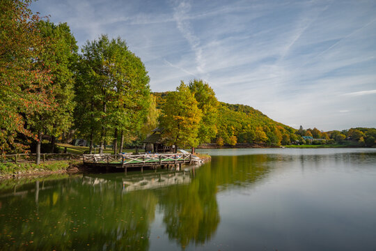 View of Pocuvadlo Lake surrounded by autumn trees and a wooden pier in Banska Stiavnica, Banskobystricky kraj, Slovakia.