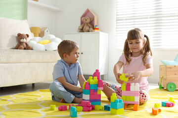 Obraz premium Little kids playing with colorful blocks on floor at home