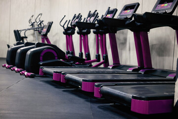 Obraz premium Gym cardio zone with exercise bikes and treadmills, selective focus