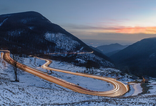 View of a winding road with car light trails through the snowy landscape of Parco Nazionale dell'Appennino Tosco-Emiliano in Sassalbo, Provincia di Massa-Carrara, Italy.