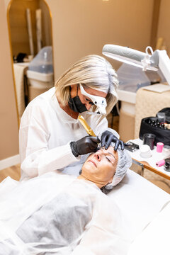 Esthetician performs microblading on a woman's eyebrows