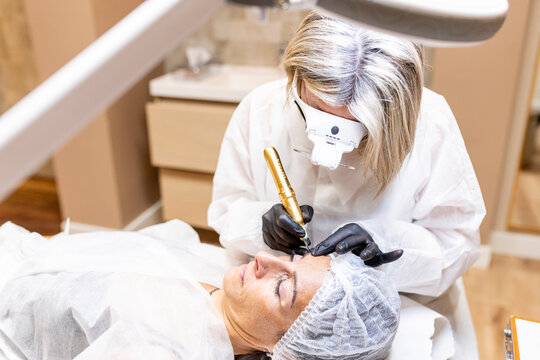 Esthetician applying permanent makeup to woman's eyebrows