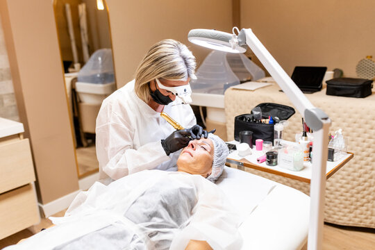 Esthetician performs microblading on woman's eyebrows