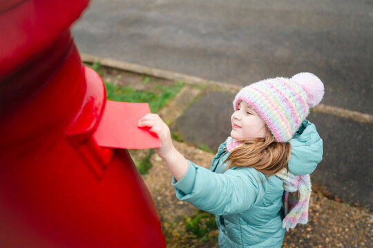 Excited girl posting letter to Santa Claus