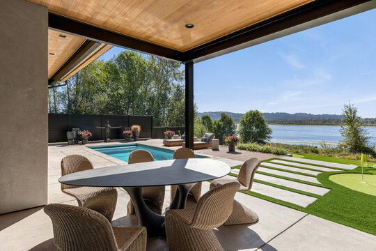 Modern home patio overlooking a pool and river, with putting green