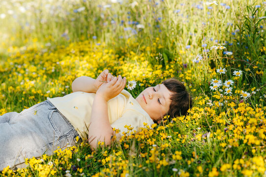 Child girl resting in wildflower meadow surrounded by yellow blooms