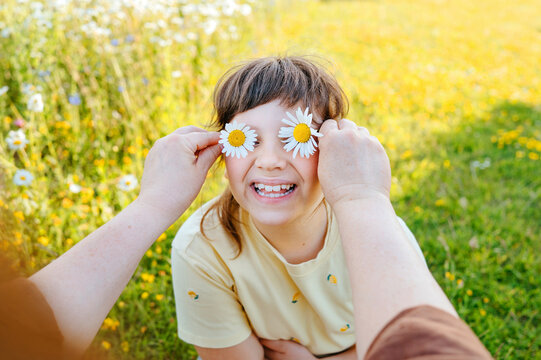 Mother holding daisy flowers over daughter's eyes