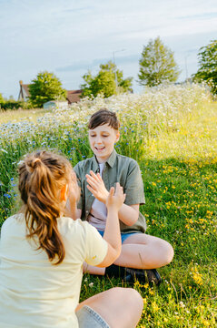 Brother and sister playing hand clapping game in wildflower meadow