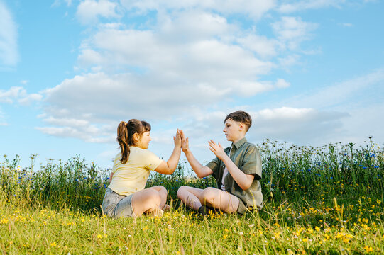 Brother and sister playing hand clapping game outdoors