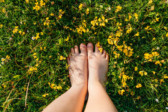 Bare feet resting on grass surrounded by yellow wildflowers
