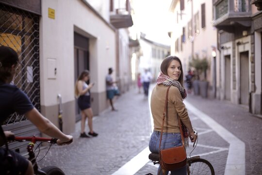 Young woman on bicycle looks back smiling on a city street