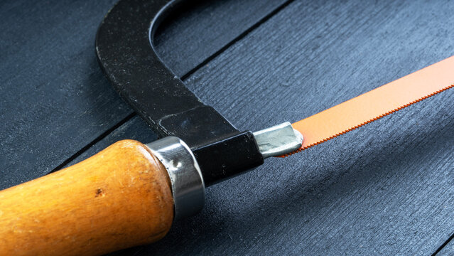 Handy saw rests on dark textured surface