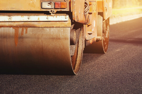 Heavy Machinery Completes Asphalt Paving on a Newly Constructed Road in a Sunny Outdoor Setting