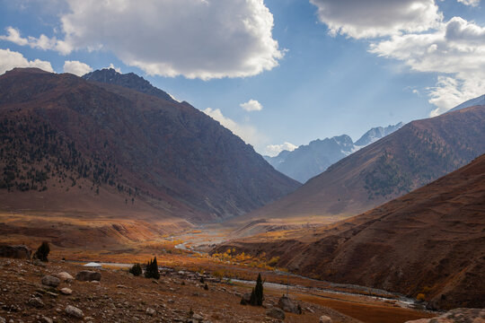 View of Astore Valley with rugged mountain slopes, a winding river, and autumn foliage under a bright sky in Astore, Gilgit, Pakistan.
