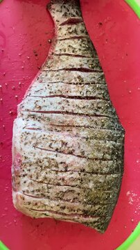 Fresh cleaned carp cut into pieces and seasoned with spices on a wooden board before baking. Preparing homemade fish dishes. Healthy protein-rich food and traditional cooking concept.