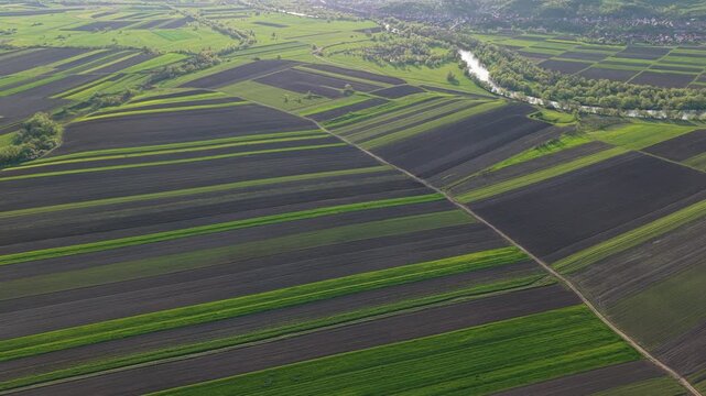 High altitude aerial of agricultural field mosaic and river in backlight